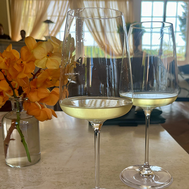 Due calici di vino bianco serviti in ambiente elegante con luce naturale